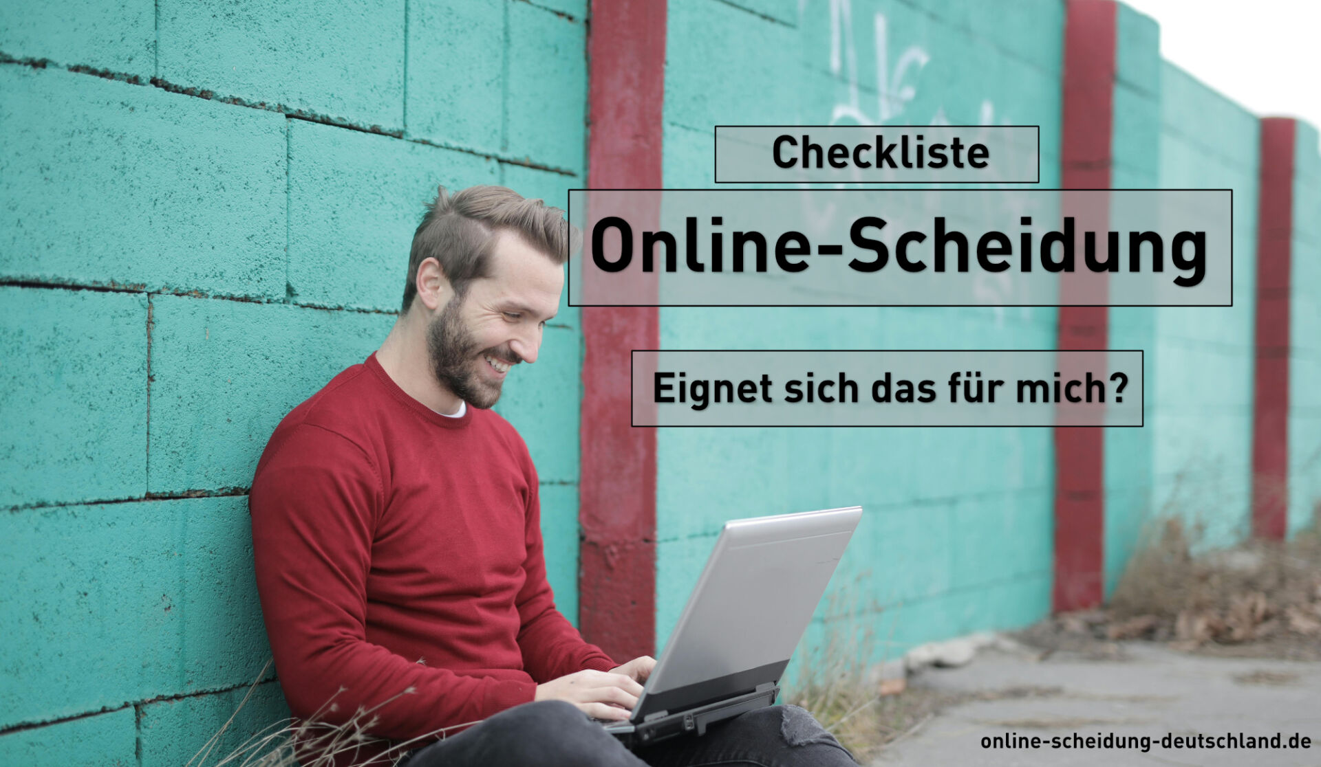 Checkliste - Online-Scheidung - Eignet sich das für mich? : Mann mir rotem Pulli sitzt vor hellblauer Wand an seinem laptop und lächelt glücklich